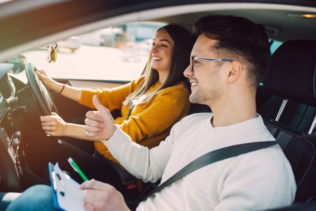 Driving instructor supporting anxious female learner driving during lesson