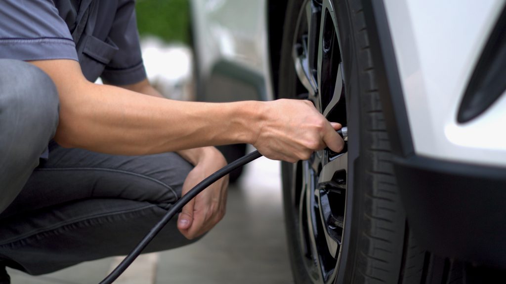 person filling air in the tires of their car 