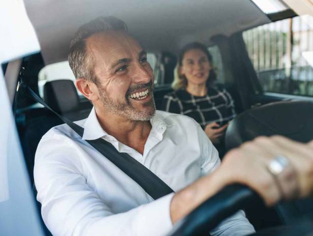 Taxi driver and passenger in car smiling