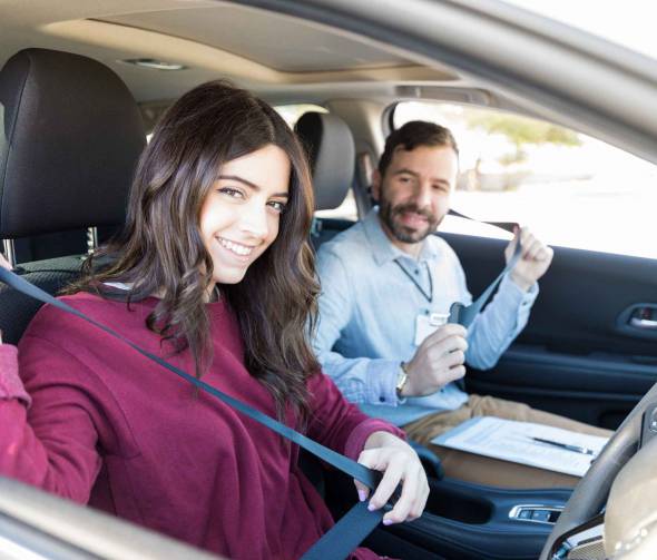 Man and women sitting in boot of car in a field. Man is pointing.