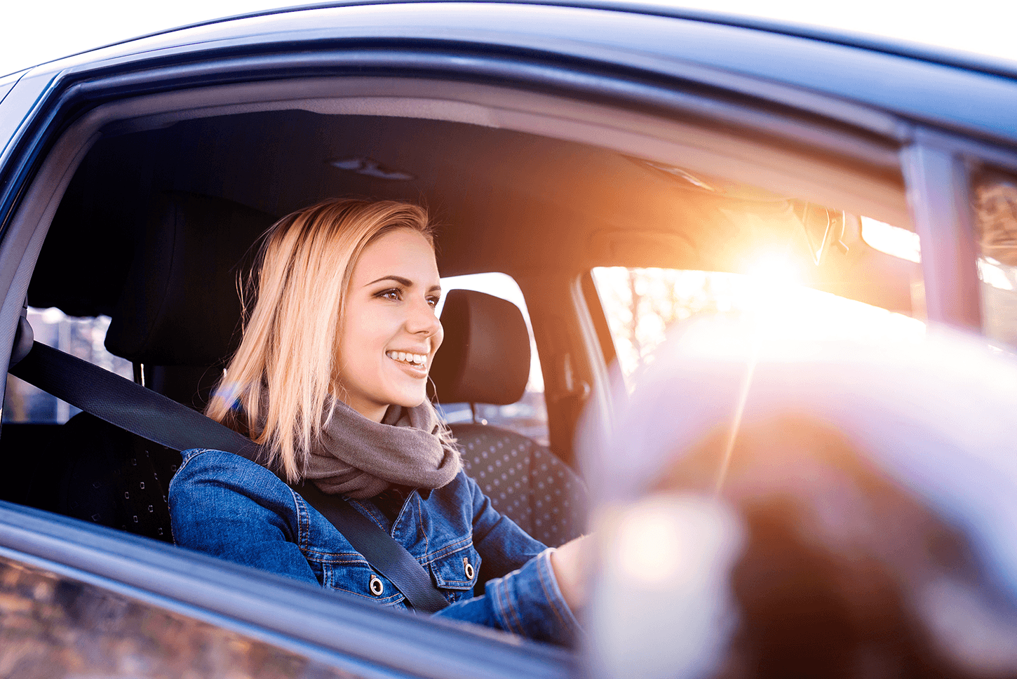 Young female learner driver in blue car with sun shining