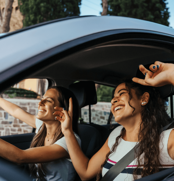 Woman learner driver in car with friend supervising.