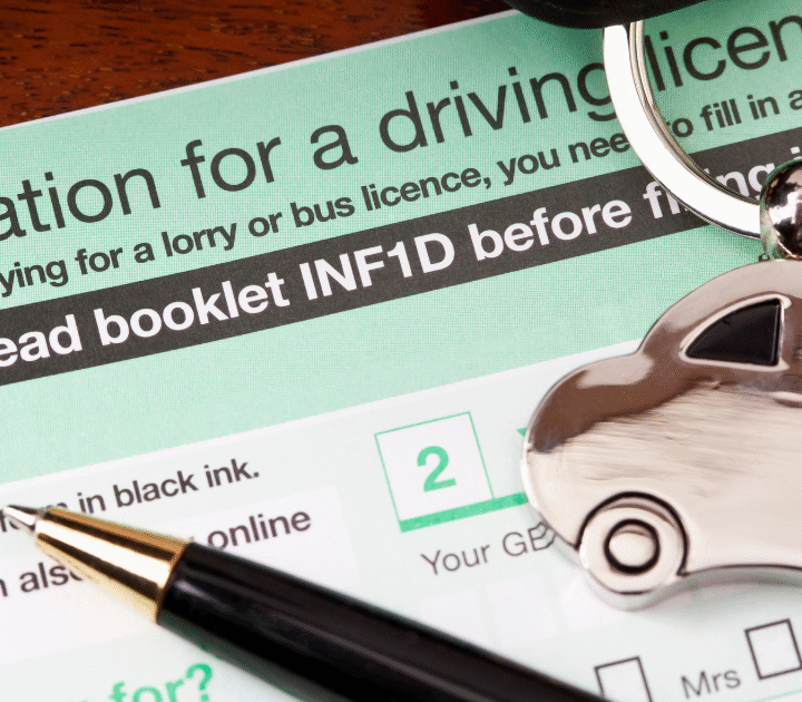 UK driving licence application form with a pen and a car-shaped keyring placed on top.