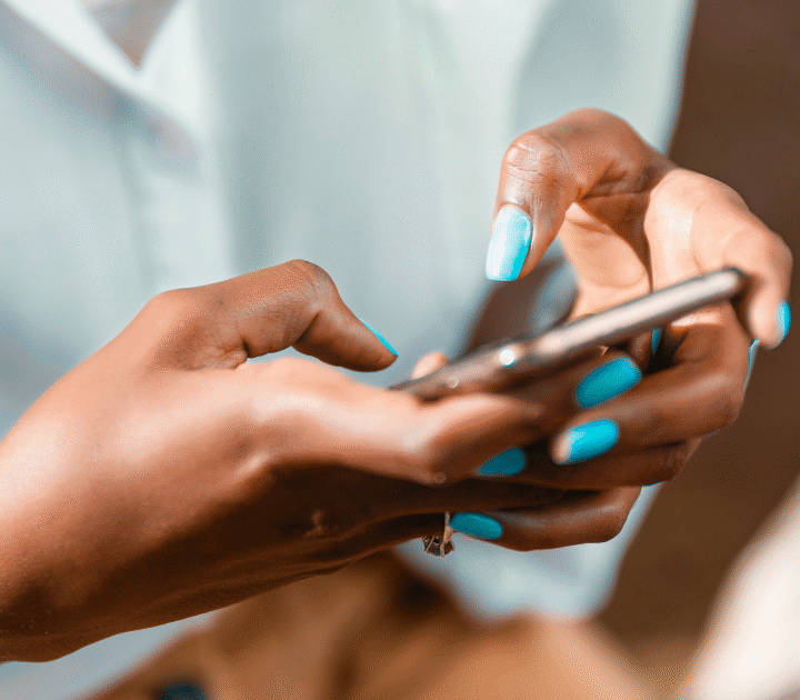 Close-up of a person with bright blue nail polish using a smartphone