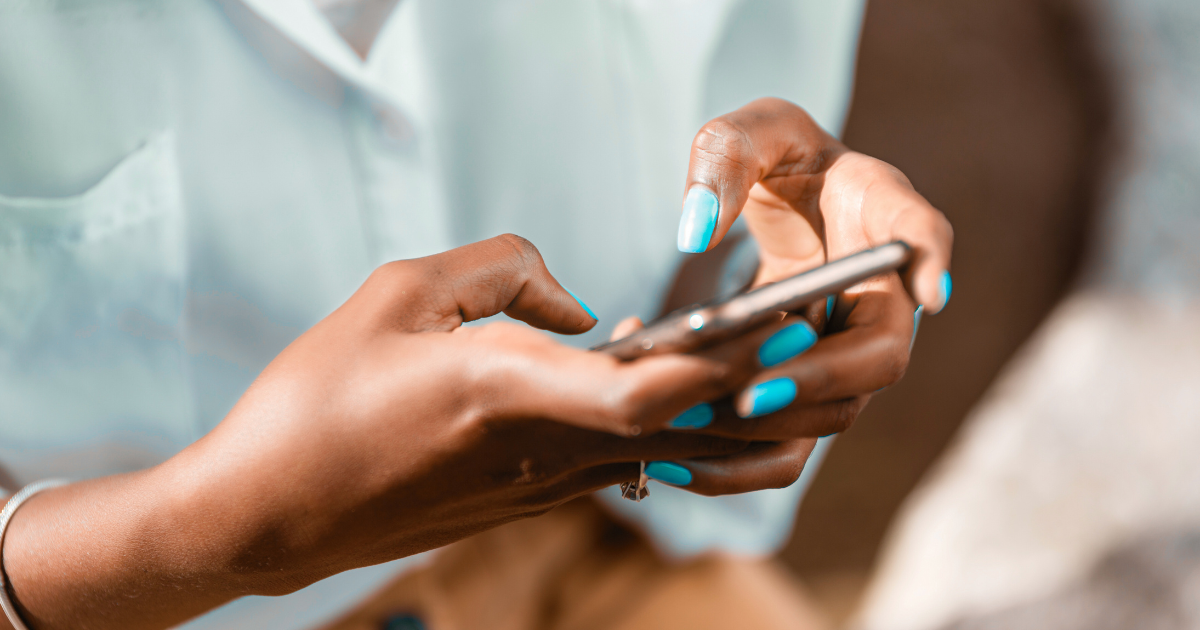 Close-up of a person with bright blue nail polish using a smartphone