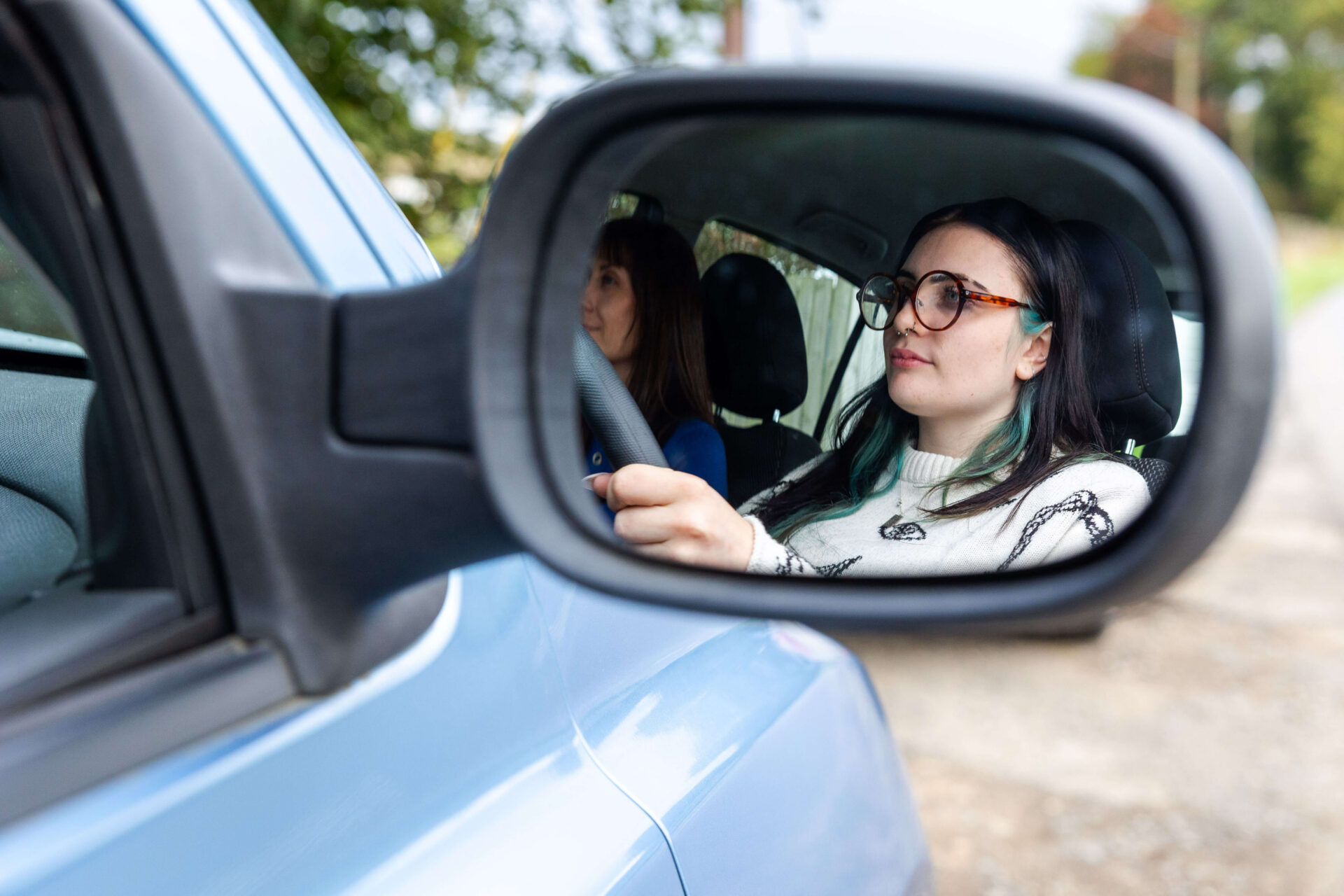 Image of girl's reflection in car wing mirror