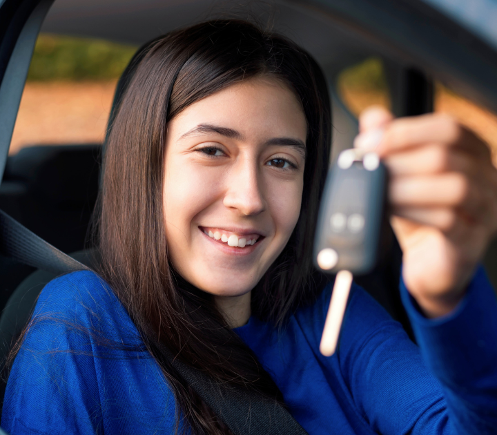 Young girl holding keys in her hand looking through the cars open window