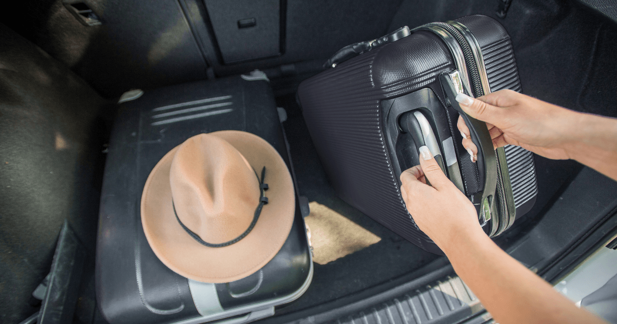 Image of person putting luggage in to car boot
