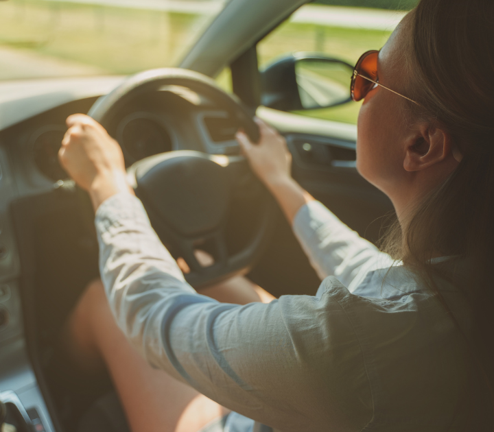 driver wearing sunglasses looking at the road ahead.
