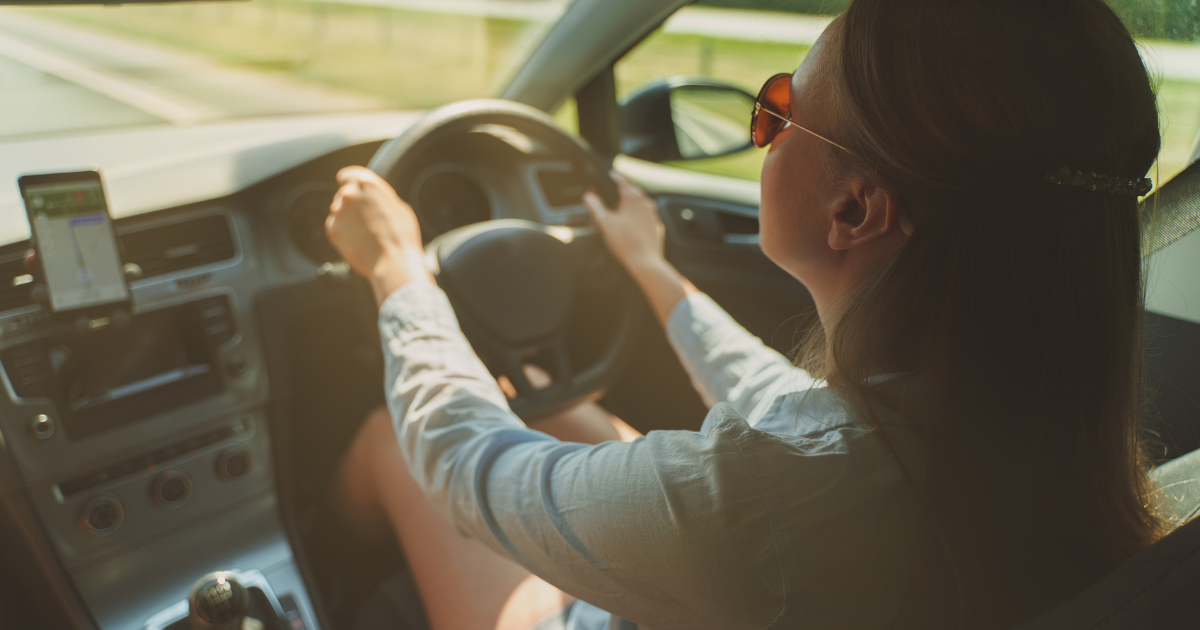 driver wearing sunglasses looking at the road ahead.