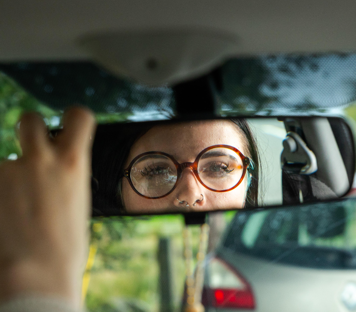 driver adjusting their rearview mirror and looking into the reflection