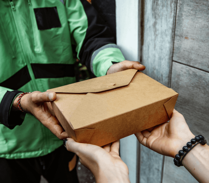 courier wearing green jacket delivering food to a customer