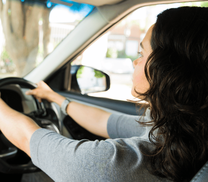 female driving student holding the steering wheel whilst inside a car