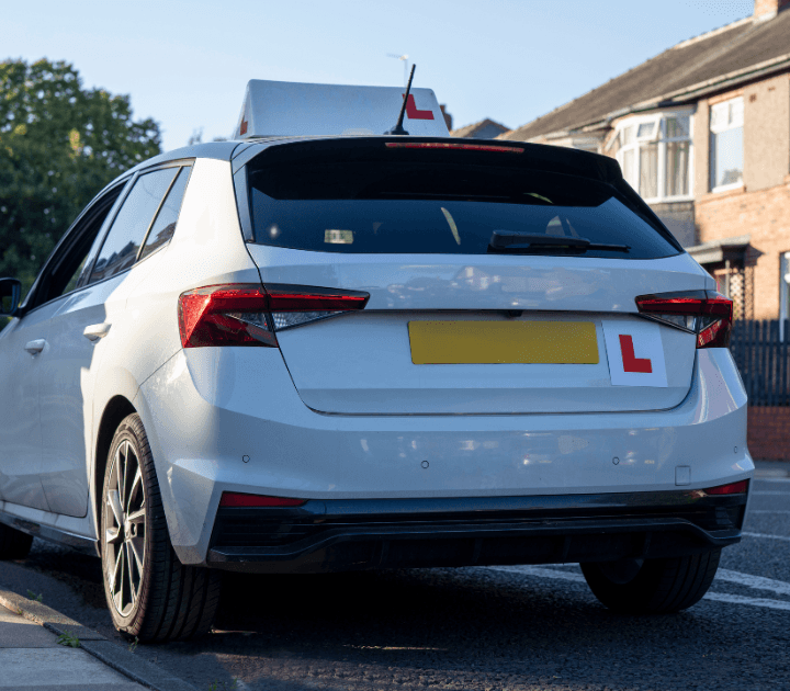 white driving instructor car with L plates on top and back of car